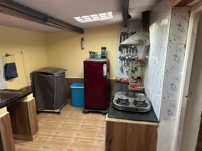 a kitchen with a stove and a red refrigerator at Kanjira house in Ooty