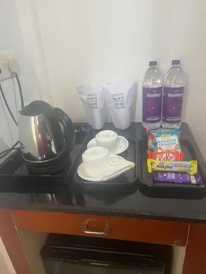 a counter top with a coffee maker and bottles of water at Nakshatra Emerald in Guruvāyūr