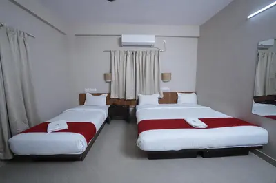 a room with three beds with red and white sheets at DREAMS AIRPORT RESIDENCY in Nedumbassery