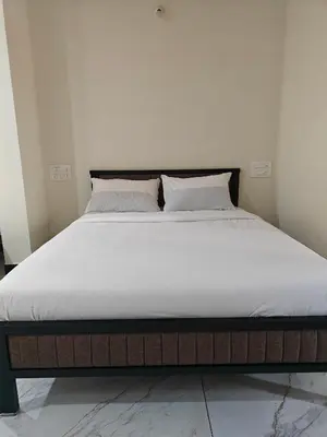 a bed with white sheets and pillows on it at Comfort Cove Apartments in Mysore