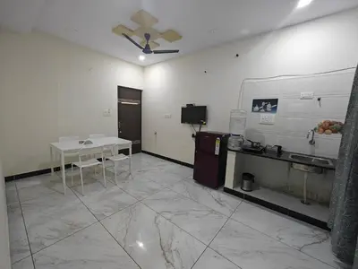 a kitchen with a counter and a table and a refrigerator at Comfort Cove Apartments in Mysore