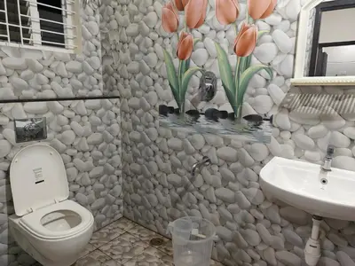 a bathroom with a toilet and a sink and flowers on the wall at Comfort Cove Apartments in Mysore