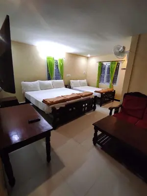 a bedroom with two beds and a couch and a table at COTTAGE GARDEN DEEPIKAS in Parambikolam