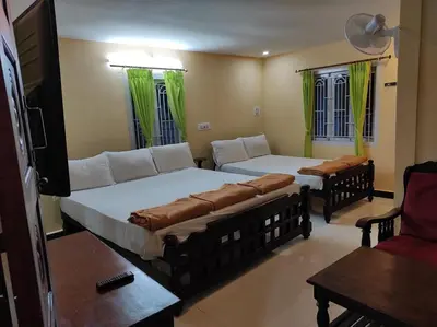 a room with two beds and a couch and a table at COTTAGE GARDEN DEEPIKAS in Parambikolam
