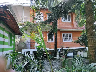 a house with a palm tree in front of it at COTTAGE GARDEN DEEPIKAS in Parambikolam