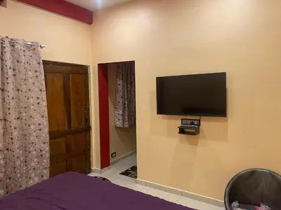 a bedroom with a flat screen tv on the wall at Four Seasons Homestay single room in Madikeri