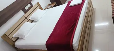 a bed with a red and white comforter and pillows at sevens residency in Sultan Bathery