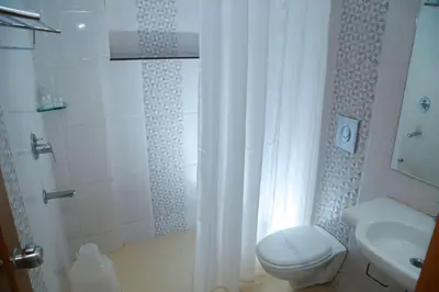 a bathroom with a shower and a toilet and a sink at Vishnu Inn in Guruvāyūr