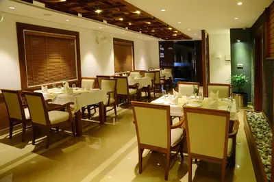 a restaurant with white tables and chairs in a room at Vishnu Inn in Guruvāyūr