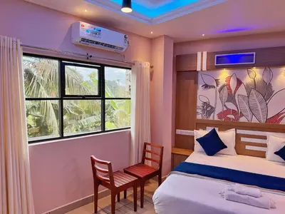 a bedroom with a bed and a window and a chair at IvyArk Residency in Pinangode