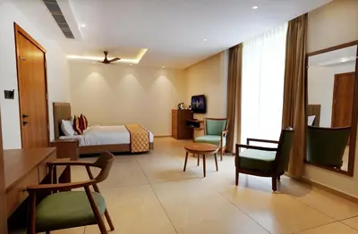 a hotel room with a bed and a desk and chairs at Bluemist Resorts in Athirappilly