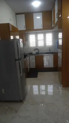 a kitchen with a refrigerator and a tile floor at DEEYA Home Stay - A Luxury Family Guest House in Mysore