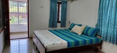 a small bedroom with a bed with blue curtains at SHI's Alaya 3BHk Villa in Coimbatore, near Railway station in Pīlamedu