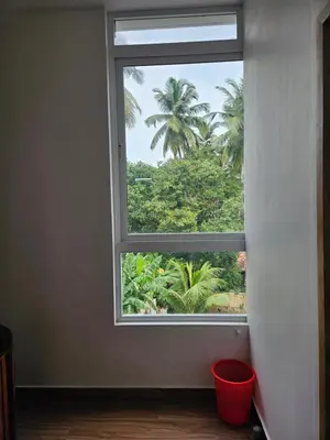 a window with a view of a palm tree at Yogis Inn in Kozhikode