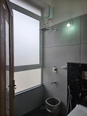 a bathroom with a window and a bucket at Yogis Inn in Kozhikode