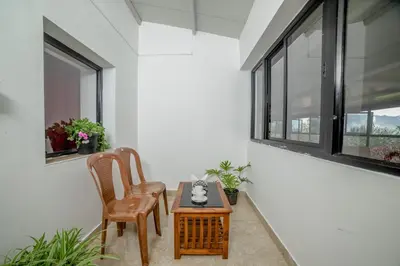 a room with two chairs and a table and windows at Shola Gardens , Kotagiri in Kotagiri