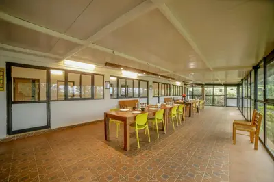 a row of tables and chairs in a room with windows at Shola Gardens , Kotagiri in Kotagiri