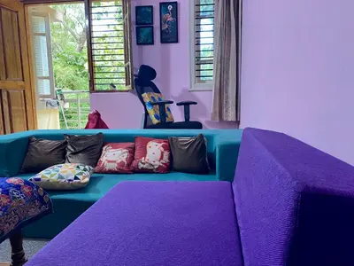 a living room with a blue couch with colorful pillows at Lovely Private Queen Bed Room in Shared 2 BHK Apartment in Mysore