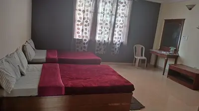 a bedroom with a bed with a red blanket on it at MYSORE MAHALAKSHMI ROOMS in Mysore