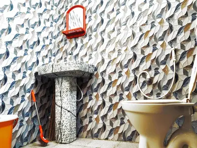 a bathroom with a toilet and a wall with a fish pattern at Mannat Inn TS Mysore - Family Homestay in Mysore