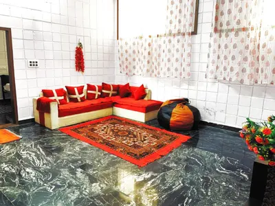 a living room with a red couch and a marble floor at Mannat Inn TS Mysore - Family Homestay in Mysore