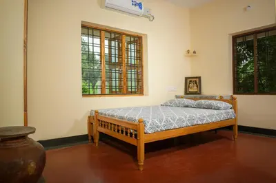a bedroom with a bed and two windows at Villa in the woods in Trichūr