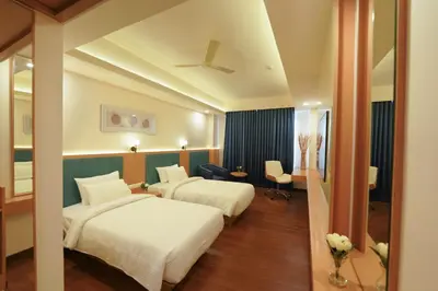 a hotel room with two beds and a mirror at Hotel Turmeric in Erode