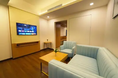 a living room with a couch and a table and a tv at Hotel Turmeric in Erode