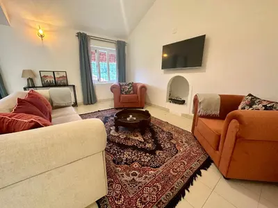 a living room with two couches and a tv at Hoopoe House, Ooty in Ooty