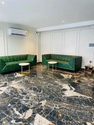 a room with two green couches and two tables at Hotel Emora Tree in Mysore