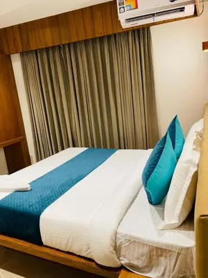 a bed with blue pillows in a hotel room at Hotel Emora Tree in Mysore