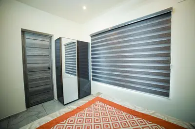 a room with blinds on the window and a red rug at Shams al Imarat in Palakkad