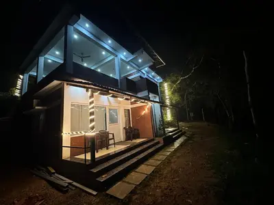 a house with blue lights on the front at night at Coorg Jungle Mist in Madikeri