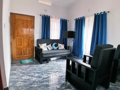 a living room with blue curtains and a couch at Moon Wings Mountain Resort in Kanthalloor