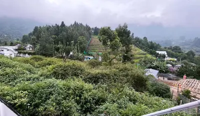 a view of a hill with trees and a town at Moon Wings Mountain Resort in Kanthalloor