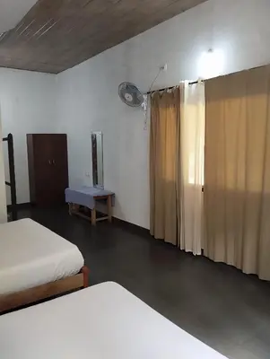 a bedroom with two beds and a window with curtains at Creek Side in Madikeri