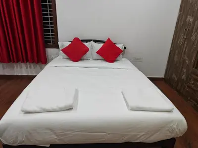 a large white bed with red pillows on it at Beautiful 4bhk Duplex Villa in Mysore