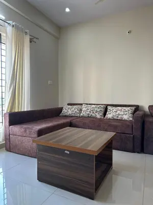 a living room with a brown couch and a coffee table at Oryx Hotel Apartments in Mysore