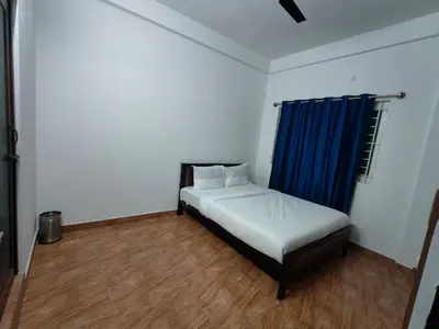a bedroom with a bed with a blue curtain at Downtown Service Apartments in Mysore