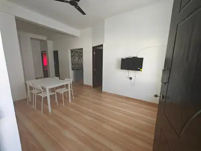 a white room with a table and chairs and a television at Downtown Service Apartments in Mysore