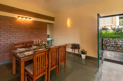a dining room with a table and chairs and a brick wall at Solitude by Nature Resorts and Stays in Kotagiri