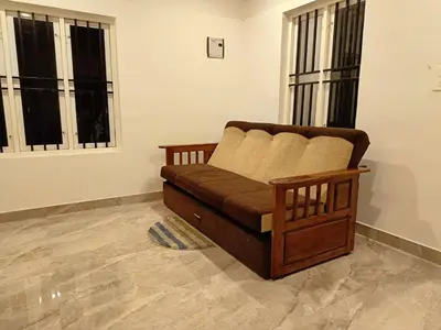 a couch in a living room with two windows at Paradise Homestay in Wayanad
