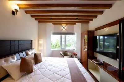 a bedroom with a large bed and a flat screen tv at Green Wood Hill Cottage in Ooty