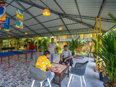 a group of people sitting around a ping pong table at The Hosteller Wayanad, Vythiri in Vythiri