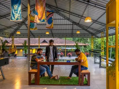three men are sitting at a table playing poker at The Hosteller Wayanad, Vythiri in Vythiri