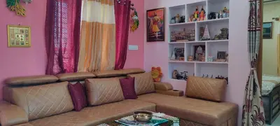 a living room with a brown couch and pink walls at Vrindavan - An Artists Nook in Mysore