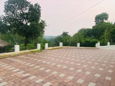 a brick parking lot with trees in the background at HappyDays HomeStay Wayanad in Chekadi