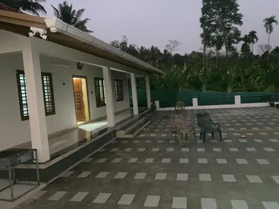 a house with two chairs sitting on a patio at HappyDays HomeStay Wayanad in Chekadi