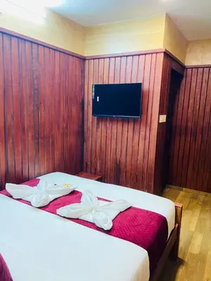 a bedroom with a bed with a tv on the wall at Mountain Mist Meadows in Ooty
