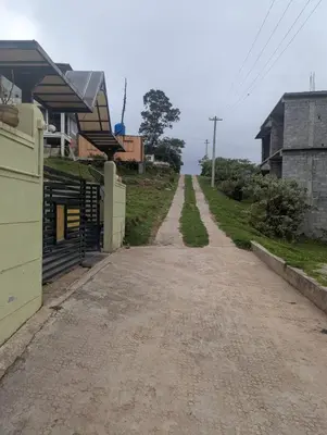 an empty dirt road next to a house at Mountain Mist Meadows in Ooty